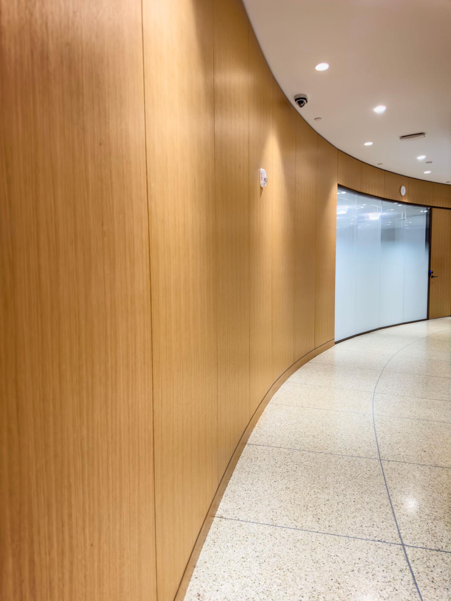 Curved oak wall paneling in a commercial corridor with terrazzo floor — Takeair Ltd carpentry London