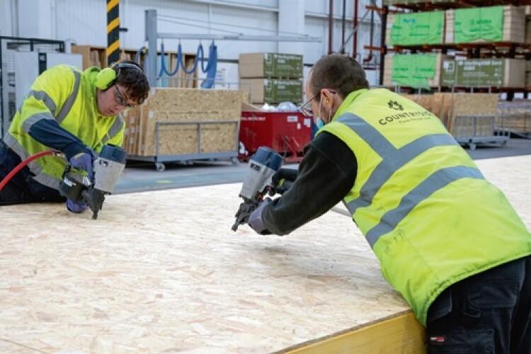 Two operatives using nail guns on OSB sheets — structural carpentry works