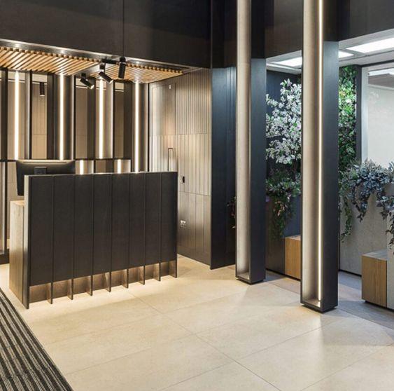 Completed dark commercial reception with timber slat feature wall, LED strip lighting, and plants