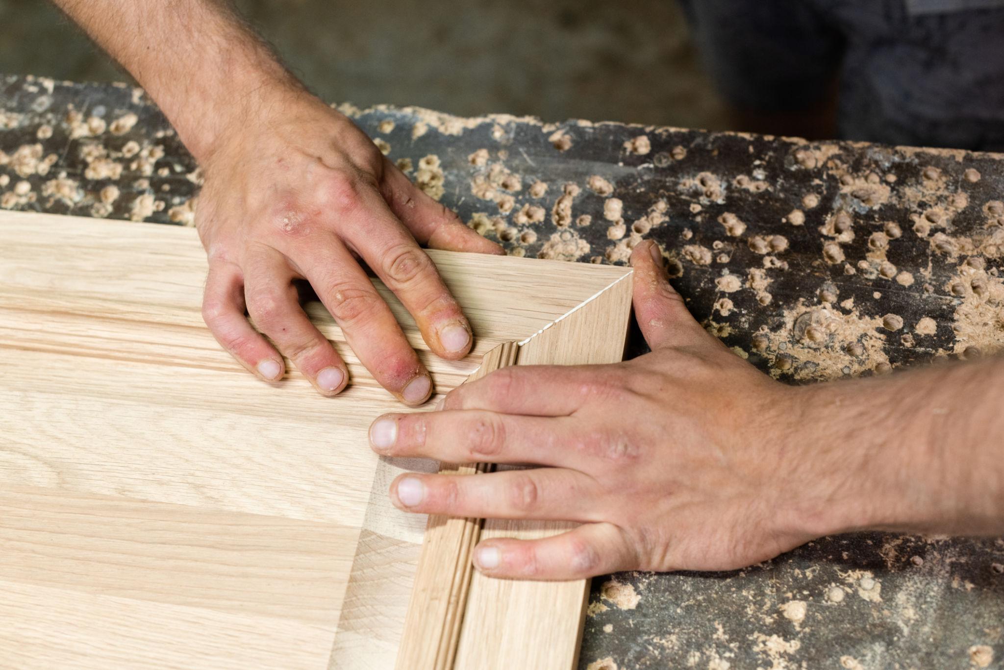 Carpenter's hands fitting a mitred skirting corner joint — second-fix finishing detail