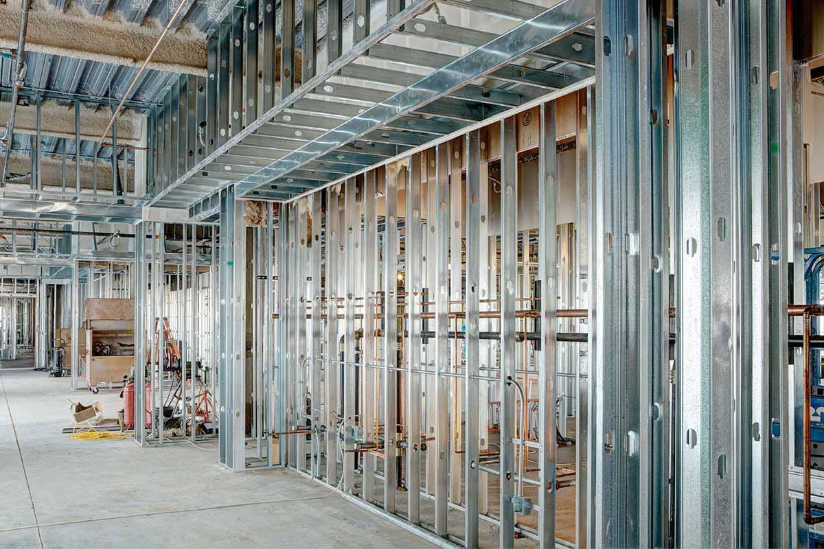Large open-plan commercial floor showing full-width metal stud framing ready for boarding