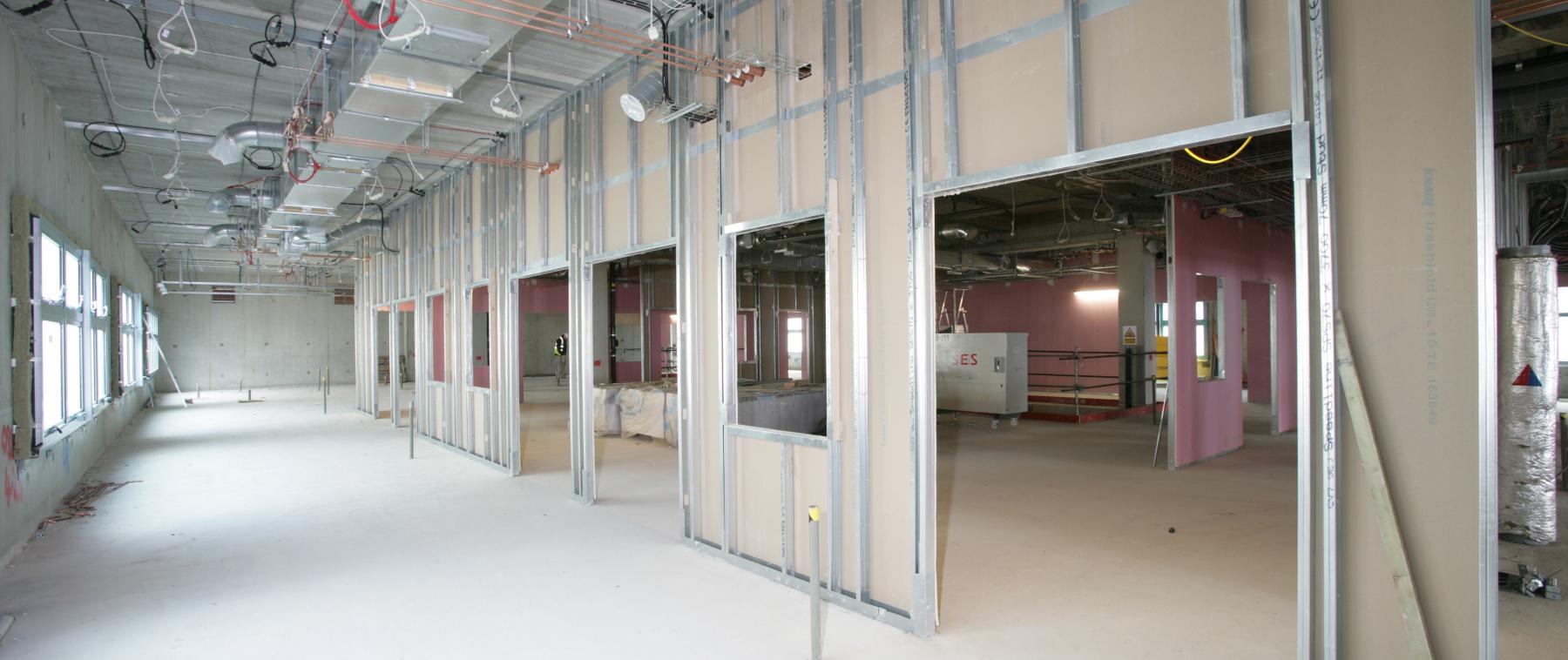 Large commercial open-plan space showing completed plasterboard partitions with multiple door openings