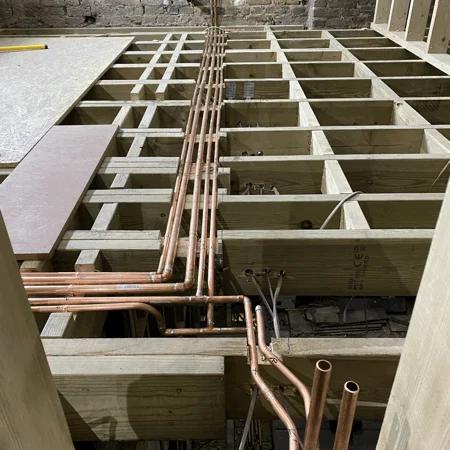 First fix copper pipework running below floor joists in a residential frame before boarding