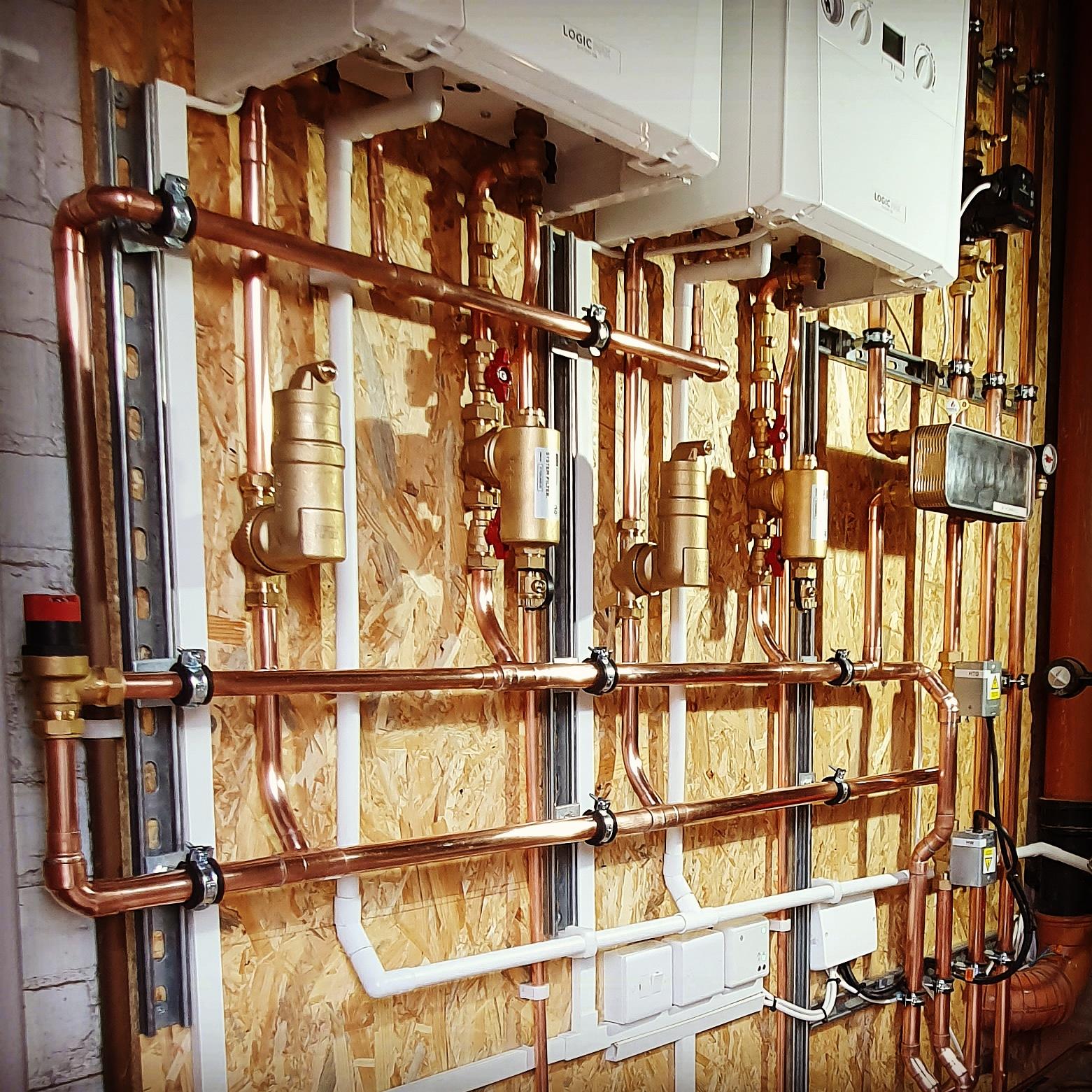 Copper pipe manifold and distribution board on OSB backing — multiple circuits neatly arranged