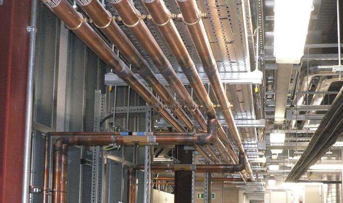 Large copper pipe runs along the ceiling of a multi-storey commercial building — Takeair Ltd plumbing London