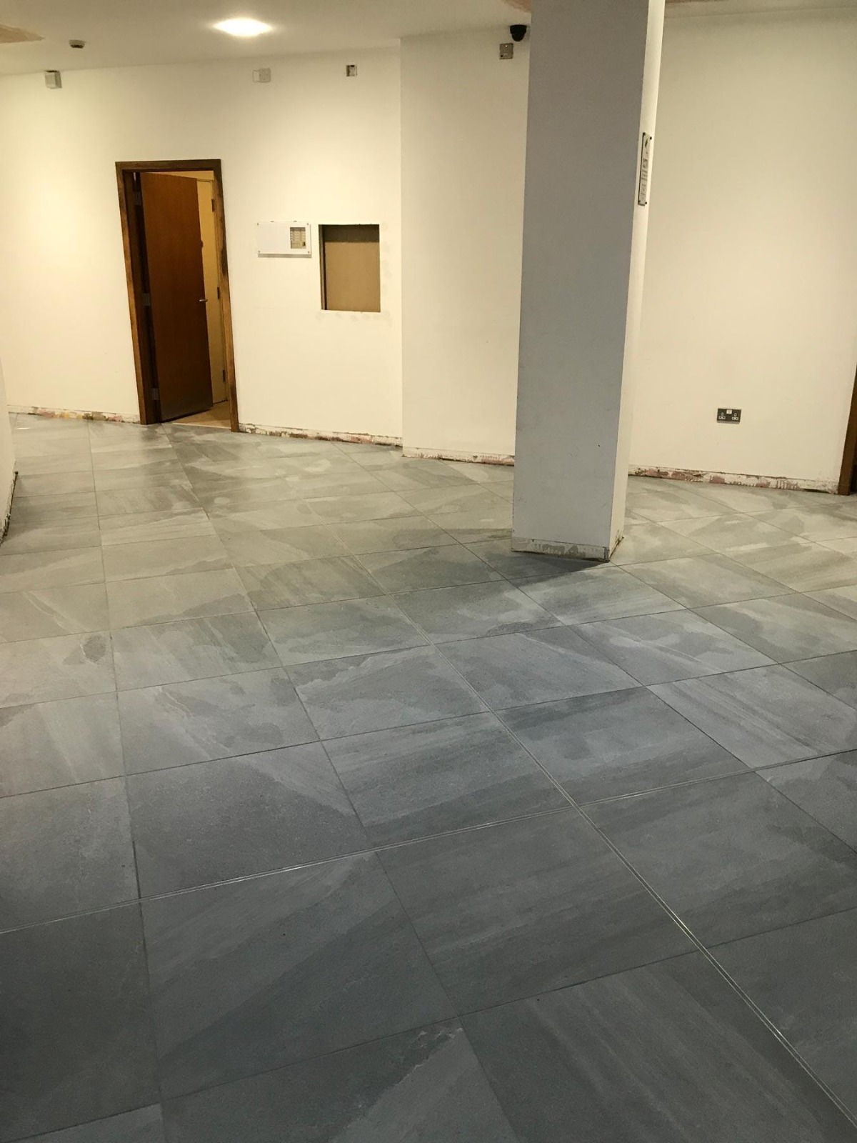 Completed large-format grey porcelain floor tiling in a commercial space