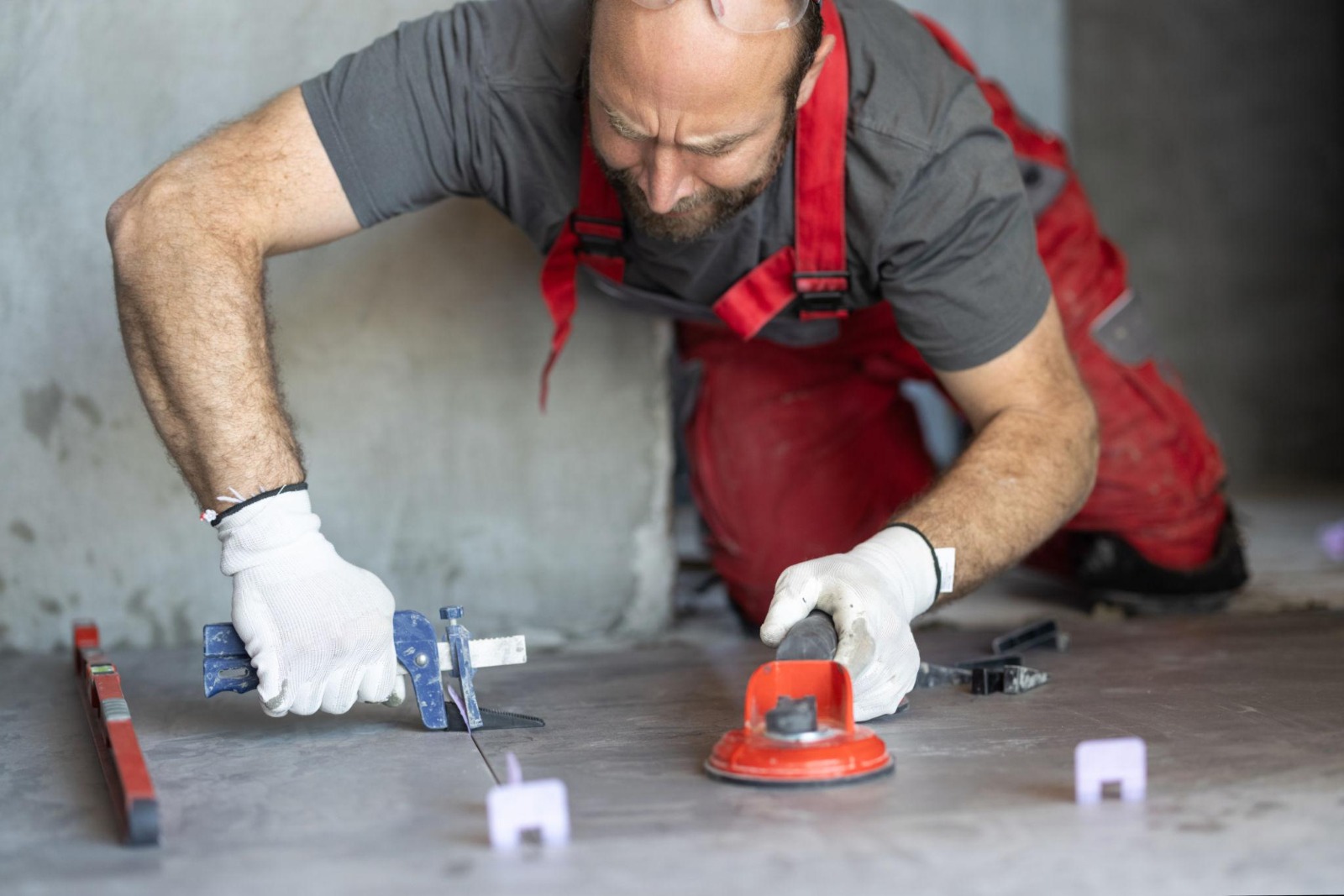 Tiler levelling large format floor tiles using suction pad and spirit level