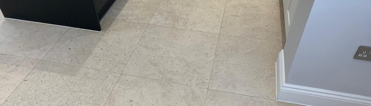 Finished cream travertine-effect floor tiles in a kitchen — completed tiling works London