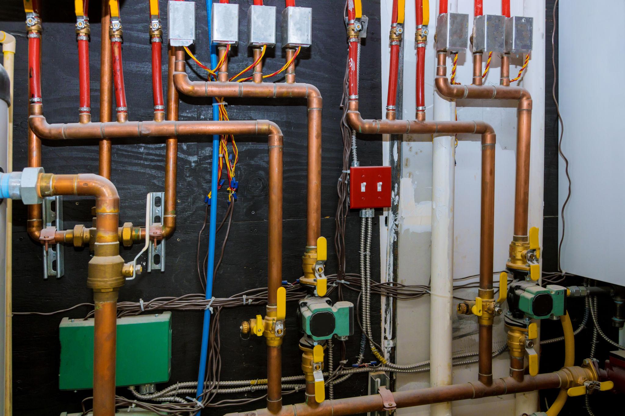 Complex copper heating distribution manifold — valves, actuators, and zone wiring