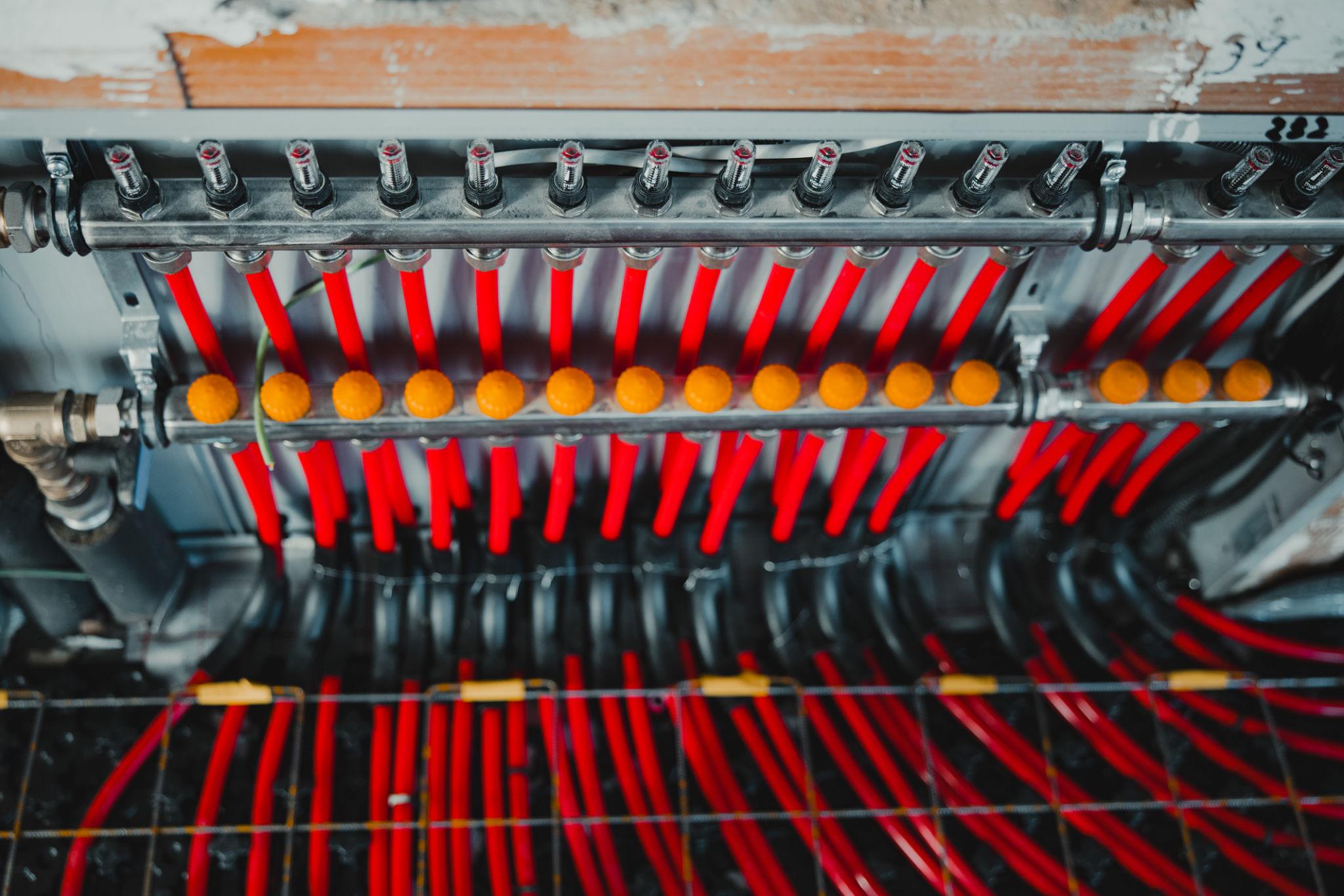 Red UFH manifold with multiple actuators — overhead view of zone distribution system