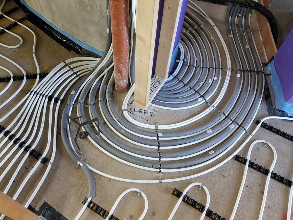 Underfloor heating pipe coiled in serpentine loops on chipboard subfloor