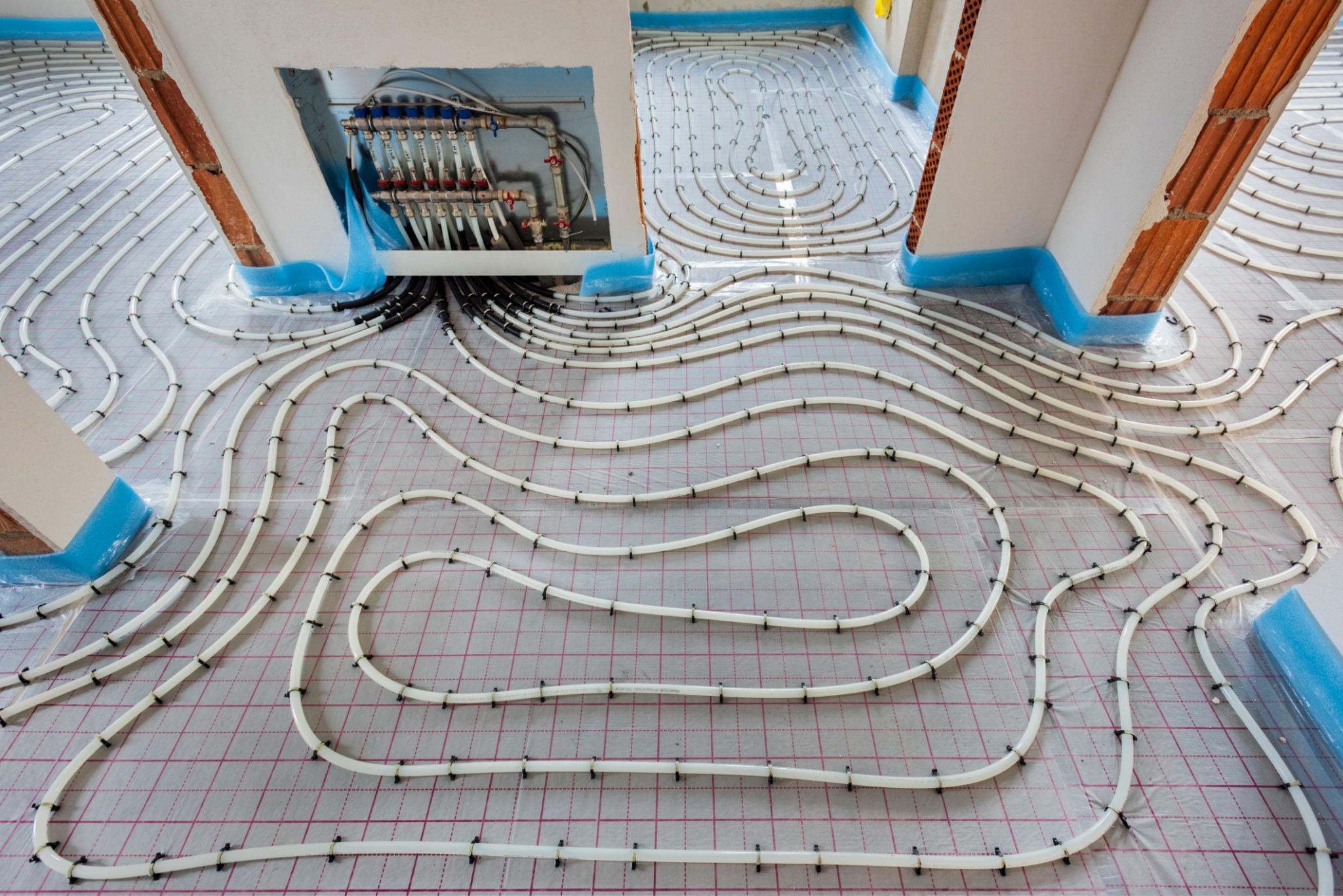 Aerial view of a whole floor plan covered in white UFH pipe loops with wall-box manifold visible